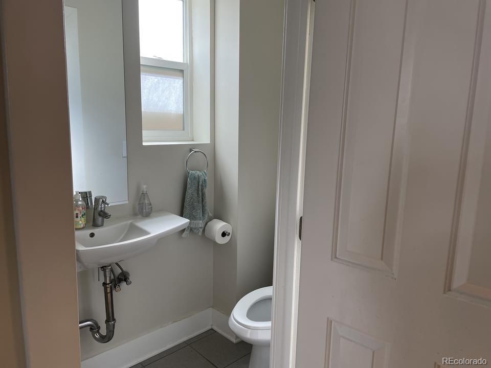 3217 Lawrence Street Denver, CO 80205 - Photo 10 of 13 a bathroom with a sink a toilet and a mirror