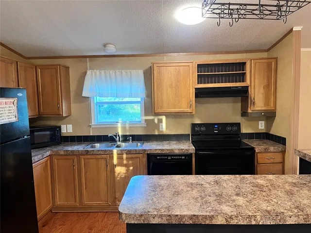 a kitchen with kitchen island granite countertop a stove top oven a sink a counter space and cabinets