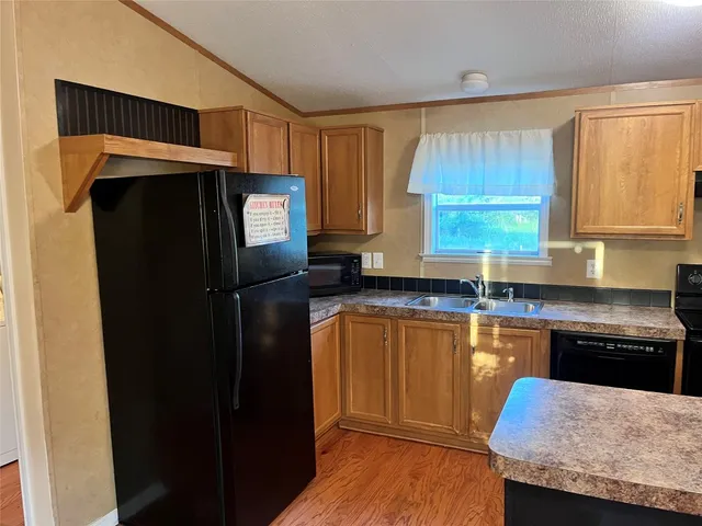 a kitchen with granite countertop wooden cabinets a refrigerator and a sink