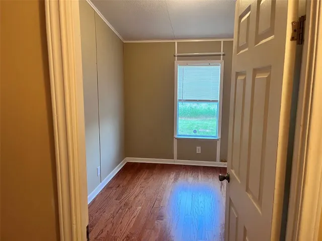 a view of a hallway with wooden floor and a window