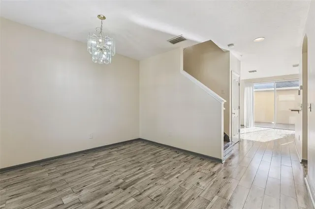 an empty room with wooden floor cabinet and windows