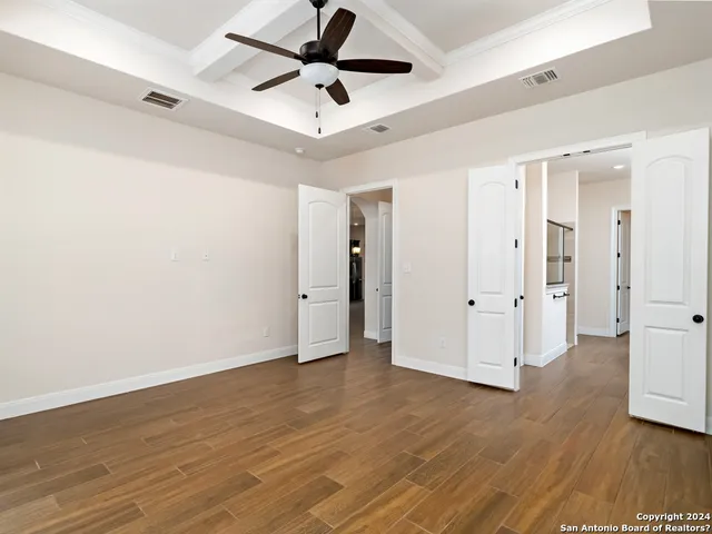 an empty room with wooden floor and ceiling fan
