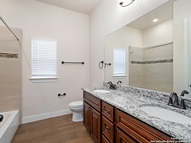 a bathroom with a granite countertop sink a toilet and a mirror