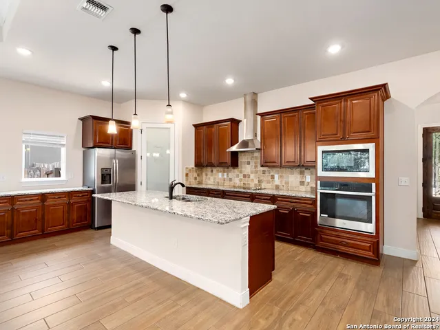 a kitchen with stainless steel appliances granite countertop a stove a sink and a refrigerator with wooden floor