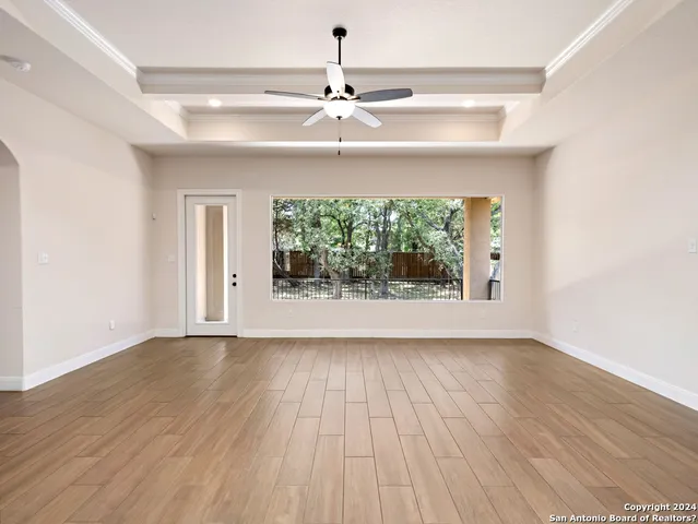 a view of an empty room with wooden floor and a window