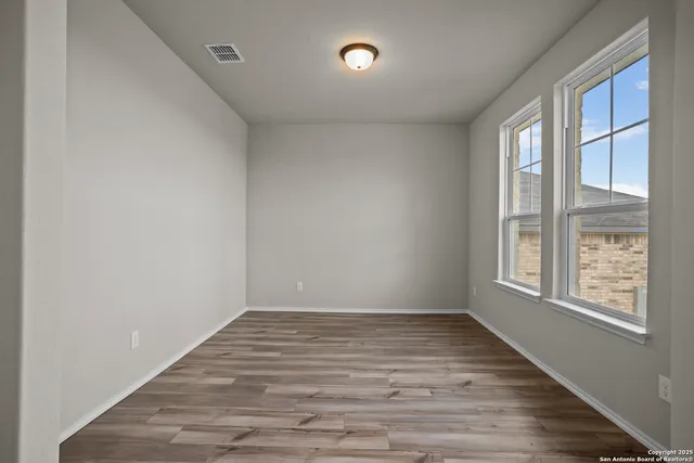 a view of an empty room with wooden floor and a window