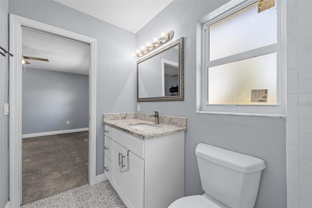 606 Bama Road Brandon, FL 33511 - Photo 26 of 44 a bathroom with a granite countertop toilet a sink and a mirror