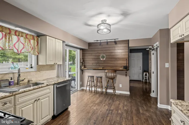 a kitchen with granite countertop a stove two sink and wooden floor