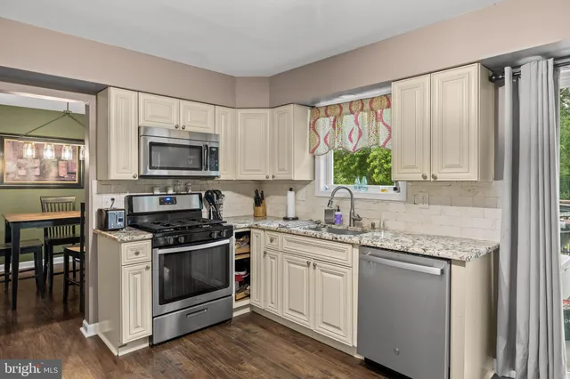 a kitchen with white cabinets appliances and a window