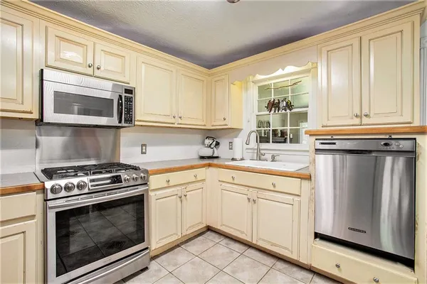 a kitchen with cabinets stainless steel appliances a sink and a window