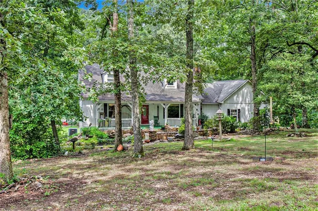 a view of a house with a small yard plants and a large tree