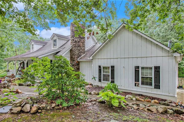 a view of a house with a small yard plants and a large tree