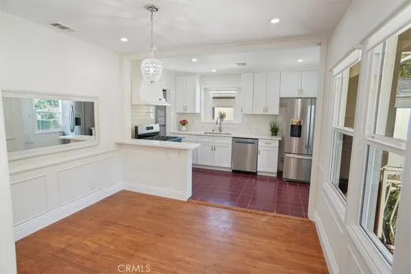 a kitchen with stainless steel appliances granite countertop a refrigerator a sink dishwasher a stove and white cabinets with wooden floor