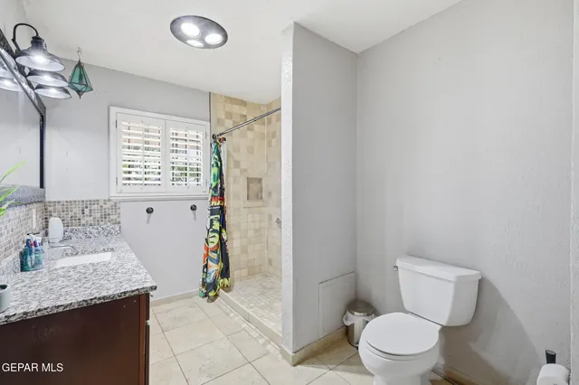 a bathroom with a granite countertop toilet a sink and a mirror