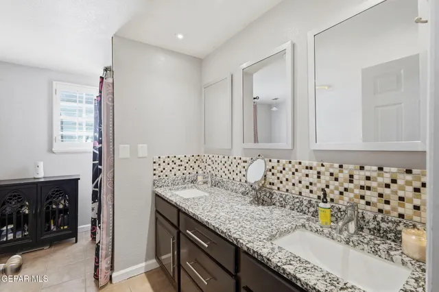 a bathroom with a granite countertop sink a mirror a vanity and a shower