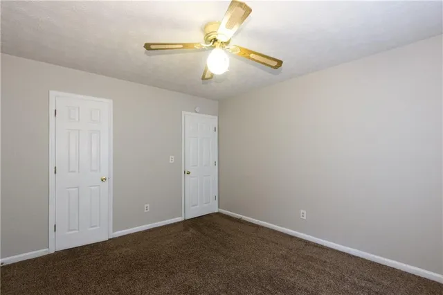 an empty room with a chandelier fan and windows