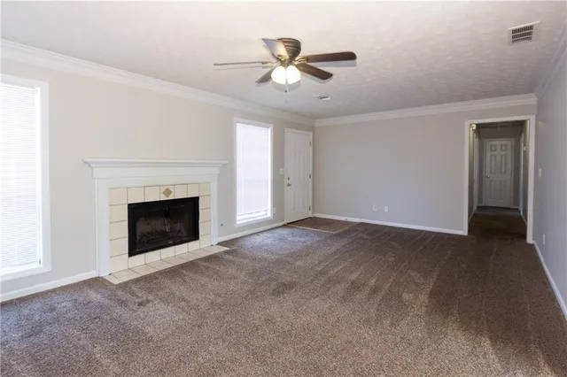 a view of an empty room with fan and kitchen view