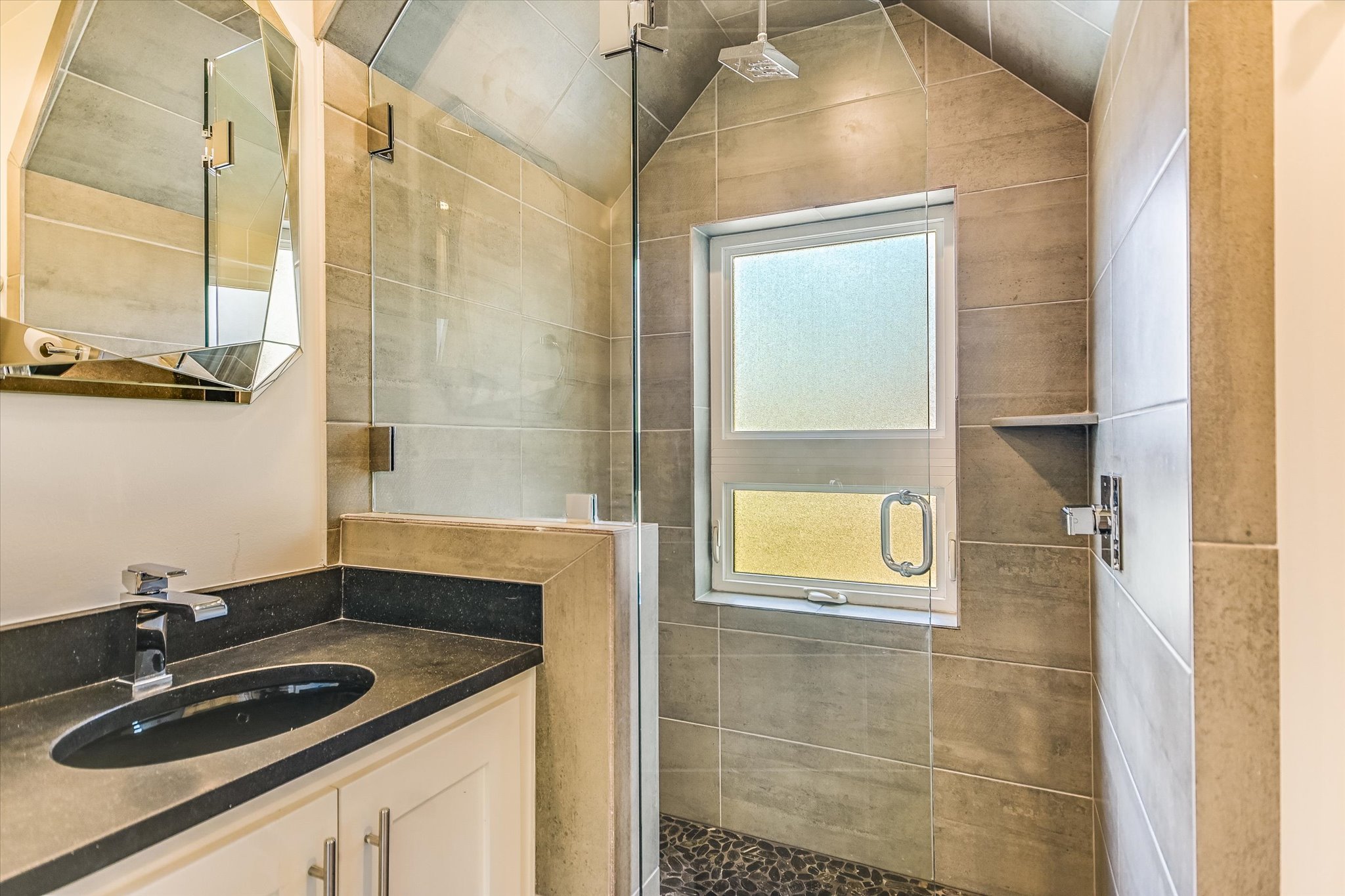 1605 Hether Street Austin, TX 78704 - Photo 25 of 26 Bathroom featuring a glass-enclosed shower with a rainfall showerhead, pebble-tiled shower floor, and a window with obscured glass