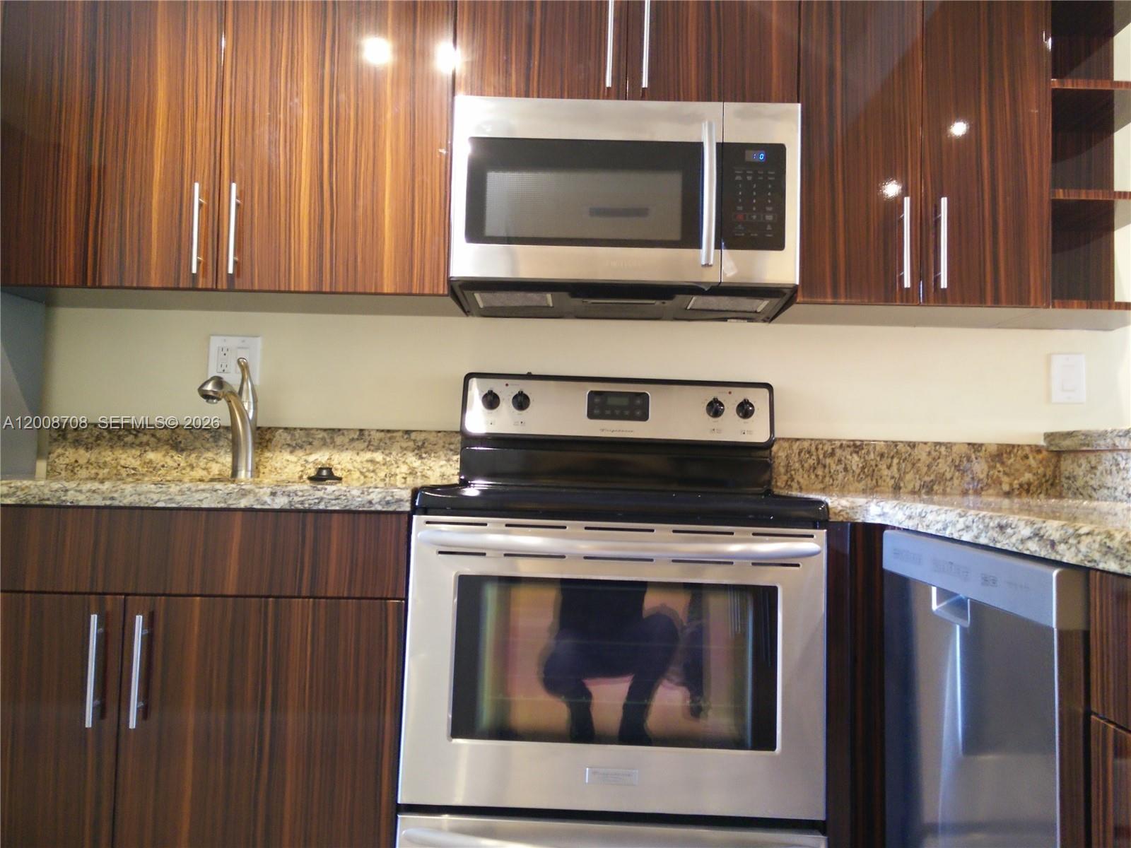 3285 Foxcroft Road, Unit E107 Miramar, FL 33025 - Photo 2 of 12 a kitchen with a stove and a microwave