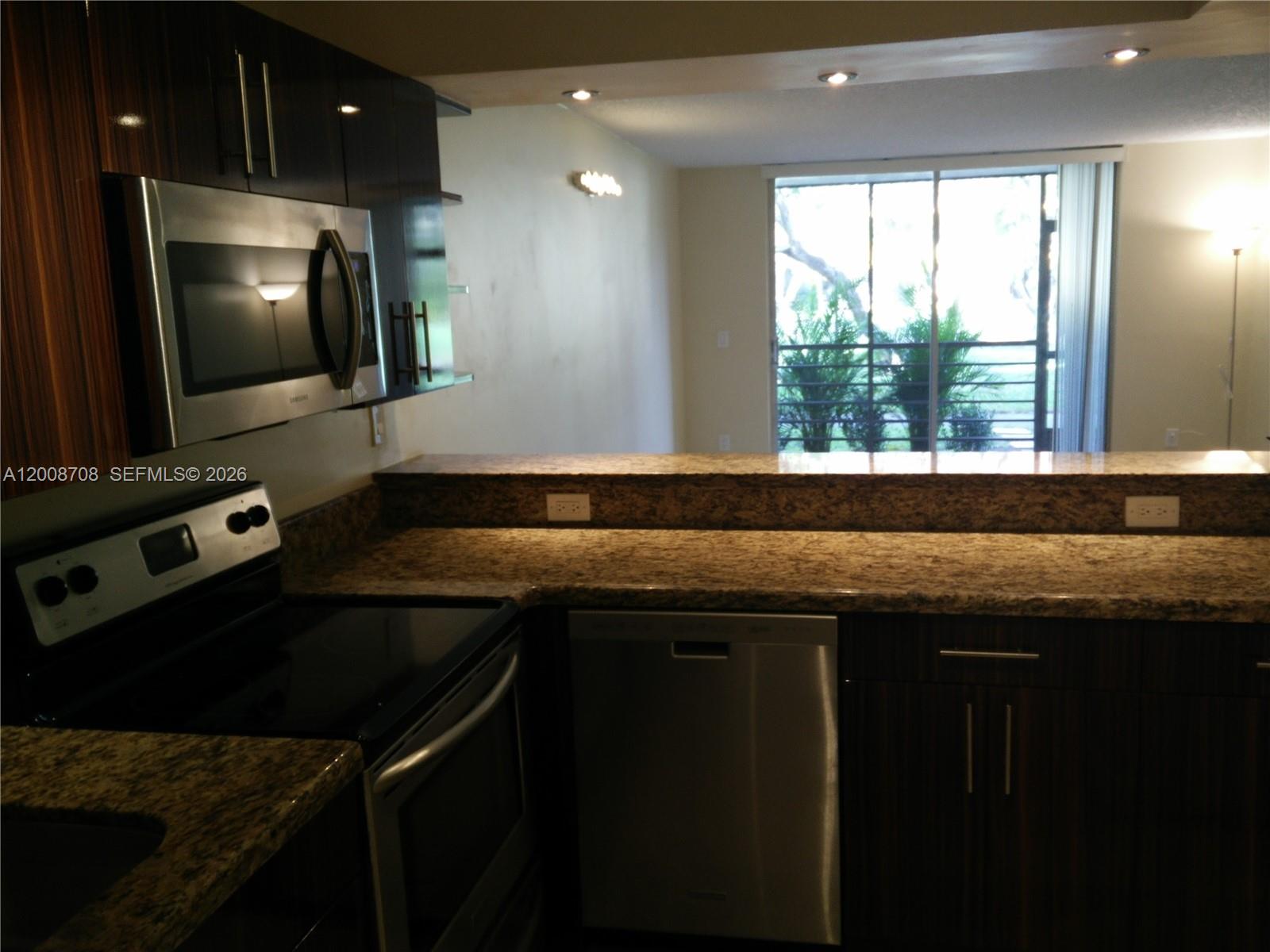 3285 Foxcroft Road, Unit E107 Miramar, FL 33025 - Photo 5 of 12 a kitchen with a sink a stove and a microwave