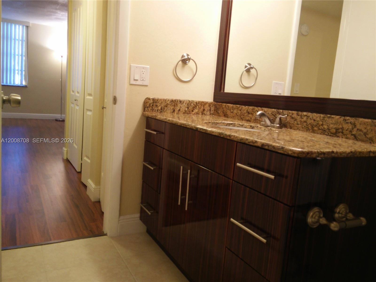 3285 Foxcroft Road, Unit E107 Miramar, FL 33025 - Photo 10 of 12 a bathroom with a granite countertop sink a mirror and shower