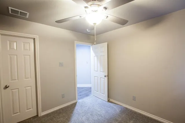 an empty room with a chandelier fan and windows