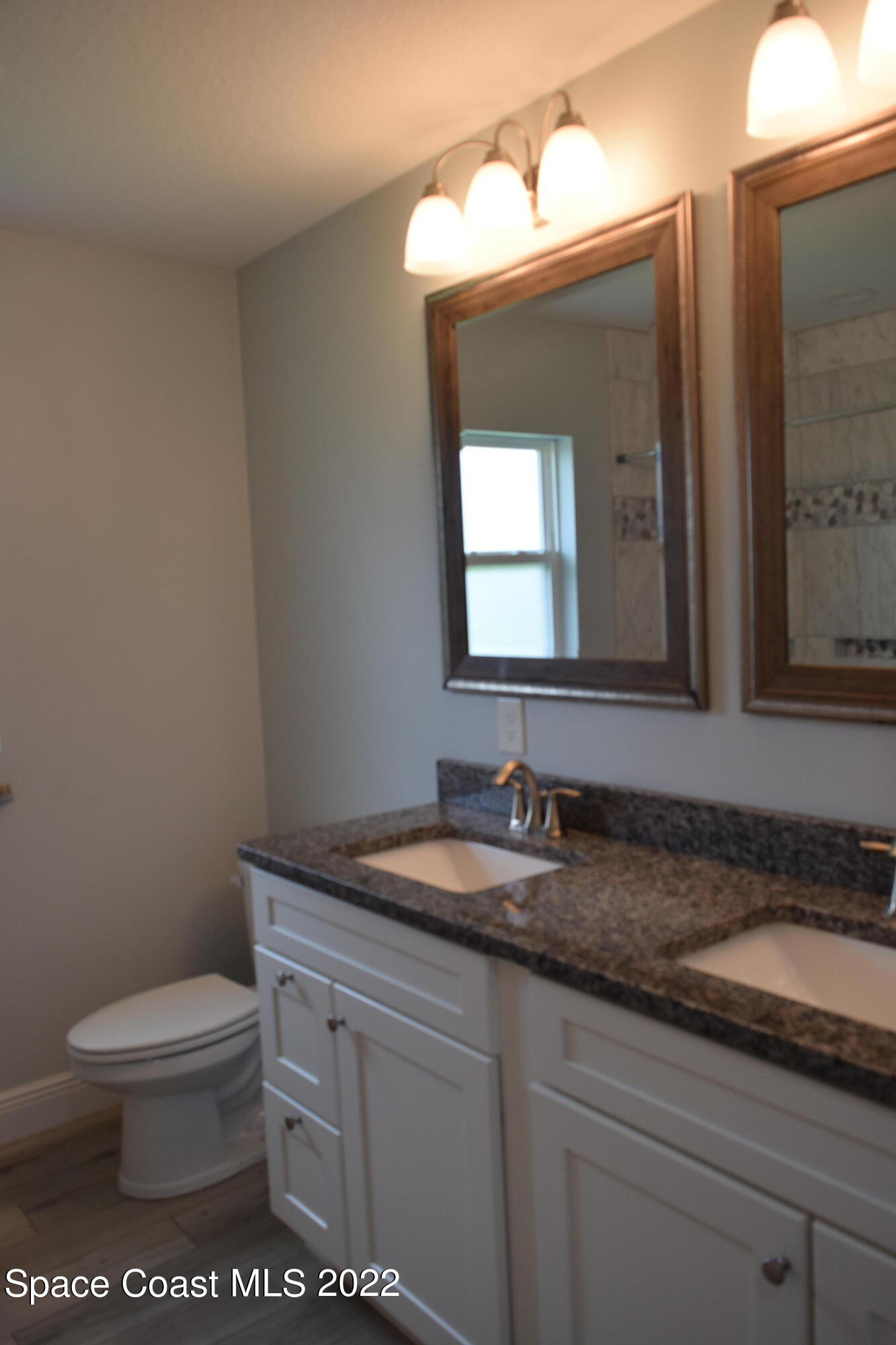 1328 Hazel Street Northwest Palm Bay, FL 32907 - Photo 16 of 28 a bathroom with a granite countertop toilet a sink and a mirror