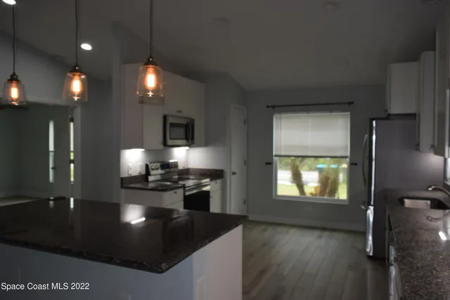 a kitchen with stainless steel appliances kitchen island granite countertop a stove a refrigerator and a microwave oven