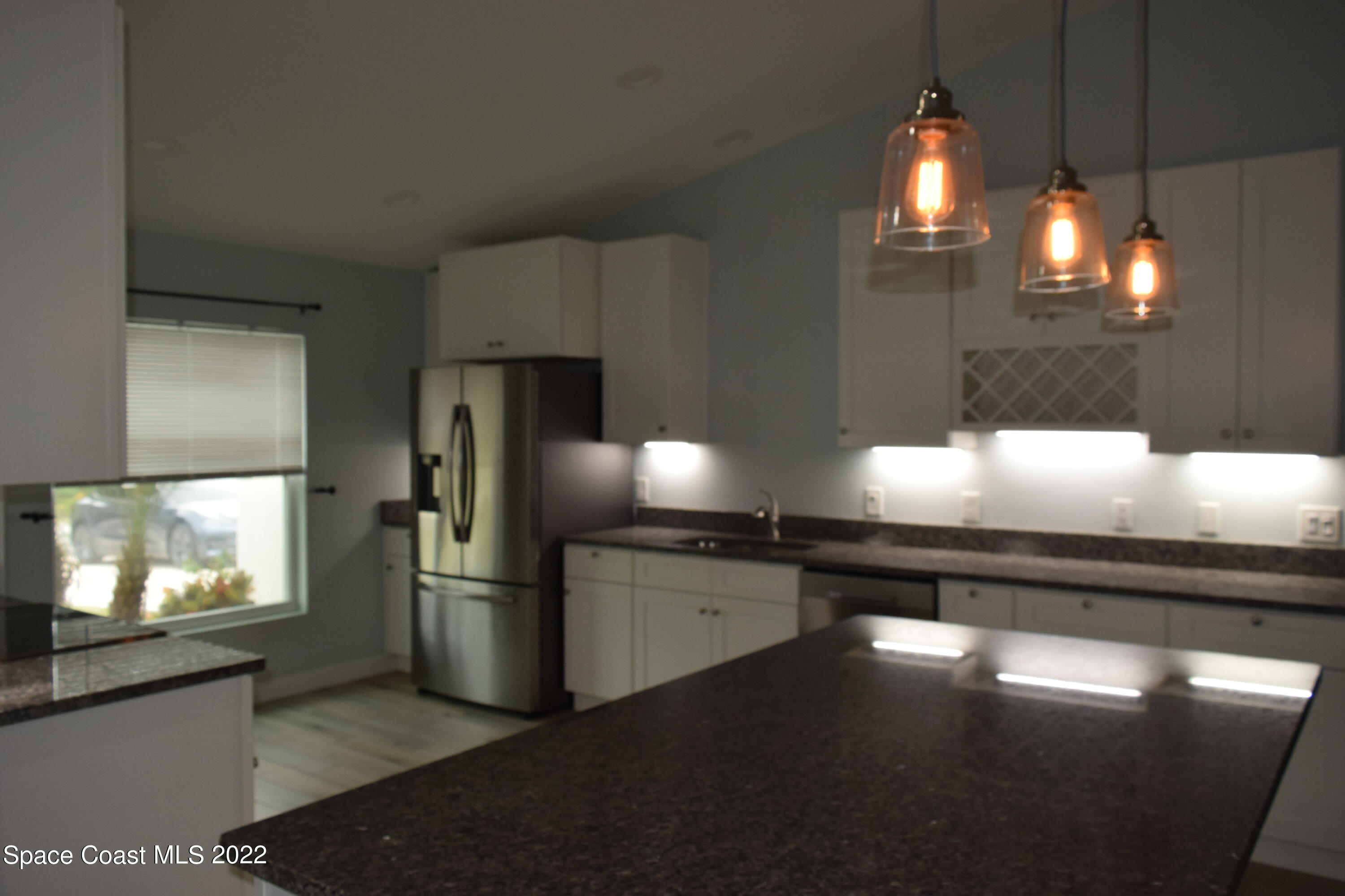 1328 Hazel Street Northwest Palm Bay, FL 32907 - Photo 5 of 28 a kitchen with stainless steel appliances kitchen island granite countertop a stove a refrigerator and a microwave oven