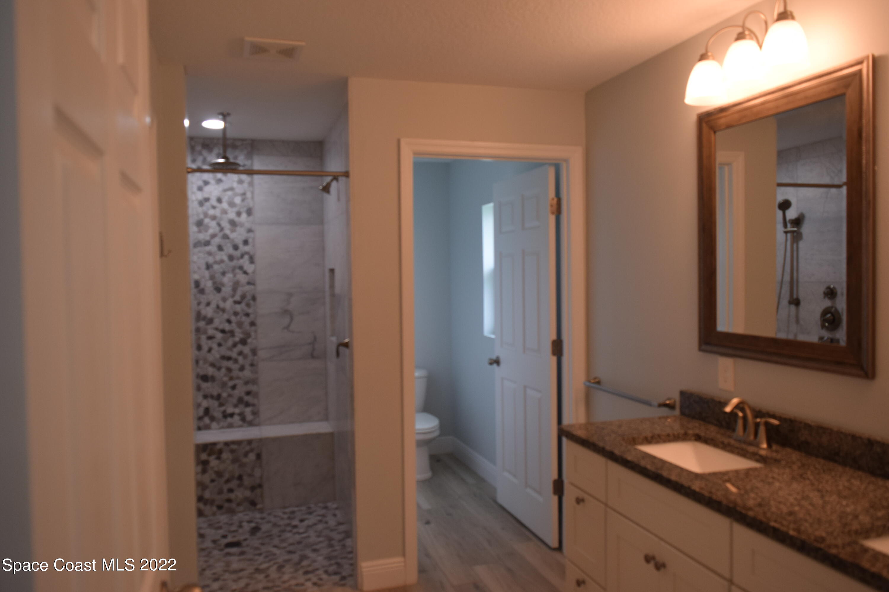 1328 Hazel Street Northwest Palm Bay, FL 32907 - Photo 9 of 28 a bathroom with a granite countertop sink a mirror and a shower