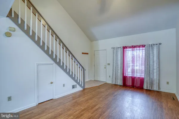 a view of an empty room with wooden floor and windows