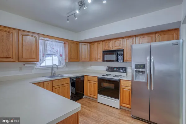 a kitchen with stainless steel appliances granite countertop a refrigerator a sink dishwasher a stove with wooden cabinets and floor