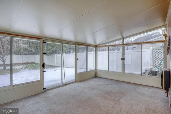 an empty room with chandelier fan and windows