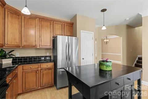 a kitchen with stainless steel appliances granite countertop a refrigerator a stove and white cabinets with wooden floors