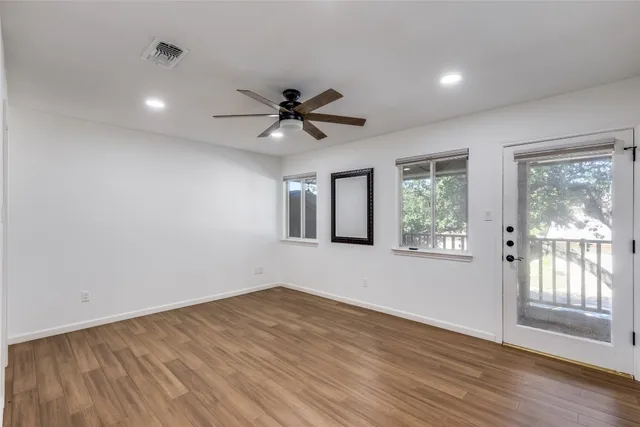 a view of an empty room with a window and wooden floor