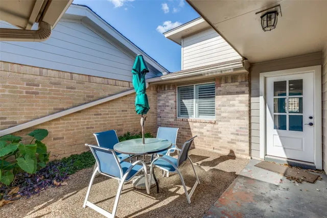 a patio with table and chairs and potted plants