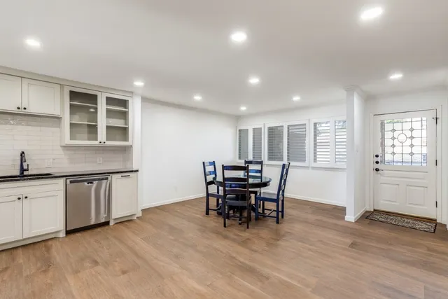a view of a kitchen with kitchen island dining table wooden floor and stainless steel appliances
