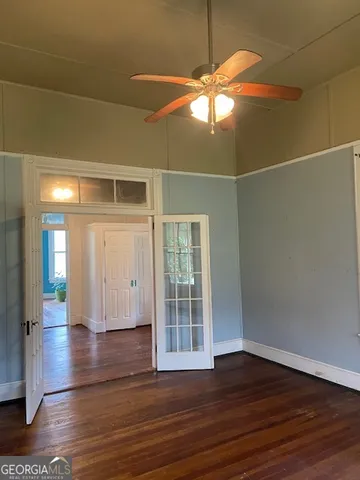 a view of an empty room with wooden floor and a window