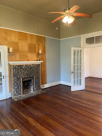 a view of an empty room with wooden floor fireplace and a window