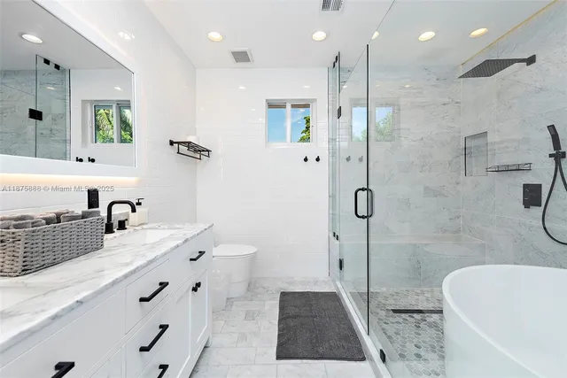 a bathroom with a granite countertop sink a toilet a mirror and shower