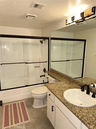 a bathroom with a granite countertop sink mirror vanity and toilet