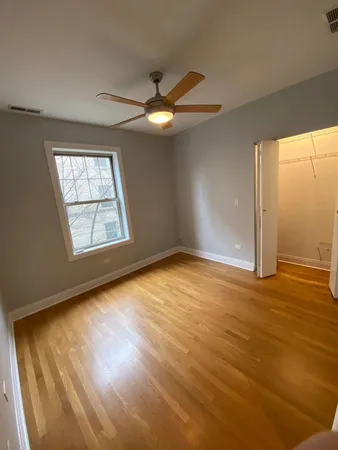 an empty room with wooden floor fan and windows