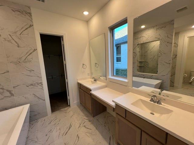 1407 Cartona Road Fate, TX 75087 - Photo 18 of 21 Bathroom featuring expansive tile flooring and walls, dual vanity with undermount sinks, and a built-in soaking tub