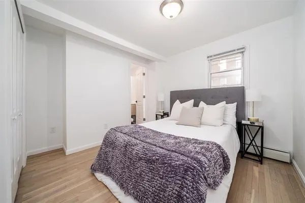 a large bed sitting in a bedroom next to a window and a wooden floor