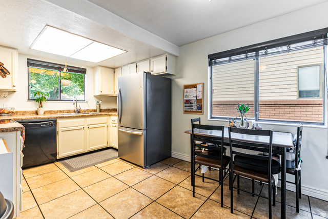 947 Canyon Road, Unit 33 Ogden, UT 84404 - Photo 5 of 19 Kitchen featuring light-toned cabinetry, a stainless steel refrigerator, black dishwasher, and tiled flooring