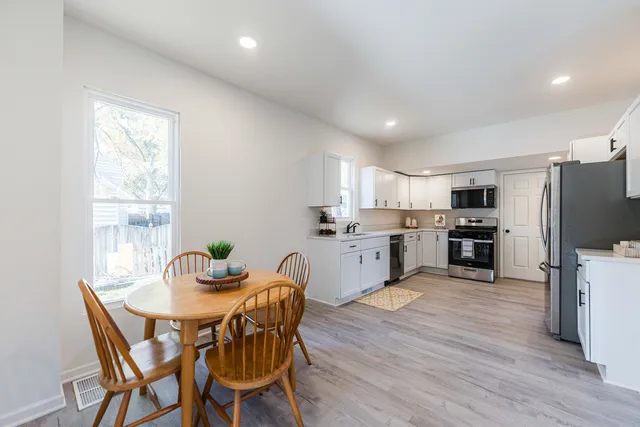 a kitchen with a table chairs microwave and cabinets