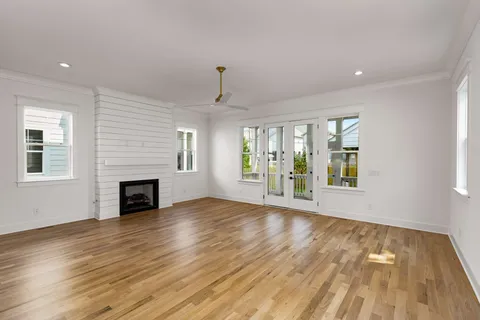 a view of an empty room with wooden floor fireplace and a window