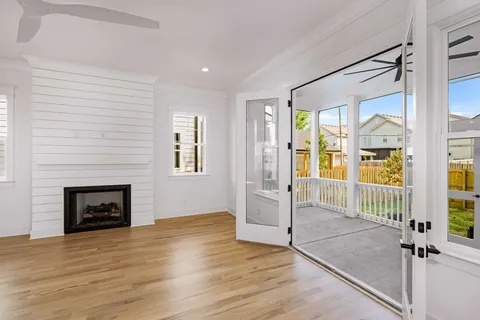 a view of an empty room with wooden floor and a fireplace