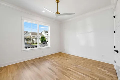 a view of an empty room with window and wooden floor