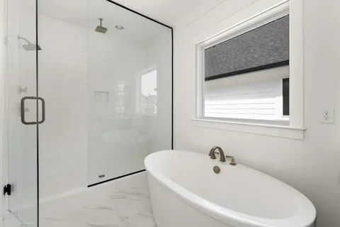 a white bath tub sitting next to a white sink and a shower